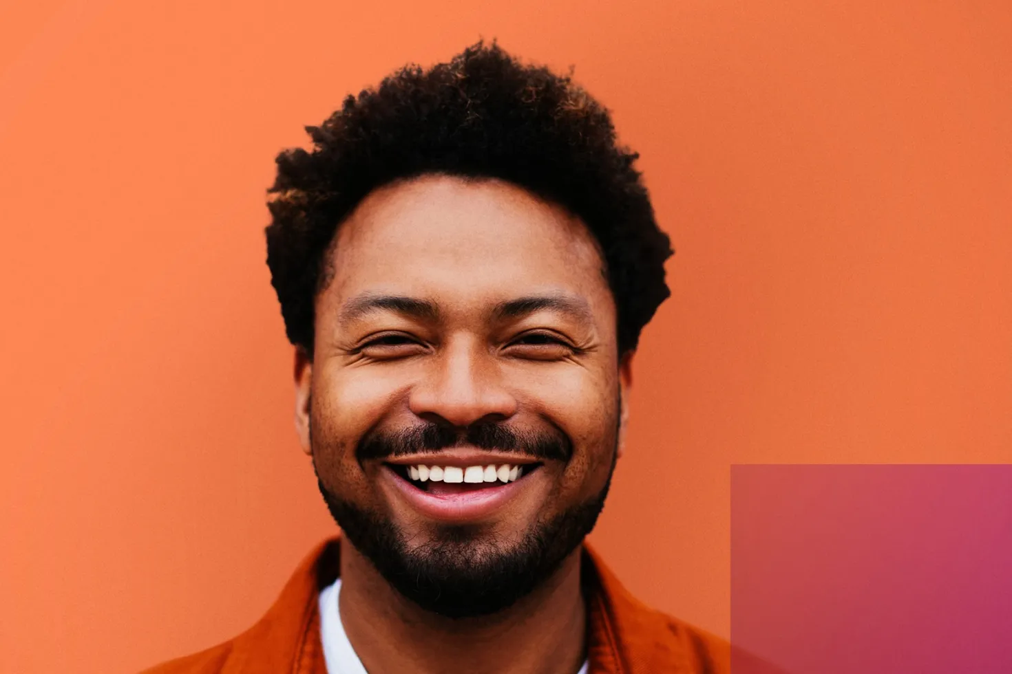 Black man smiling with orange background