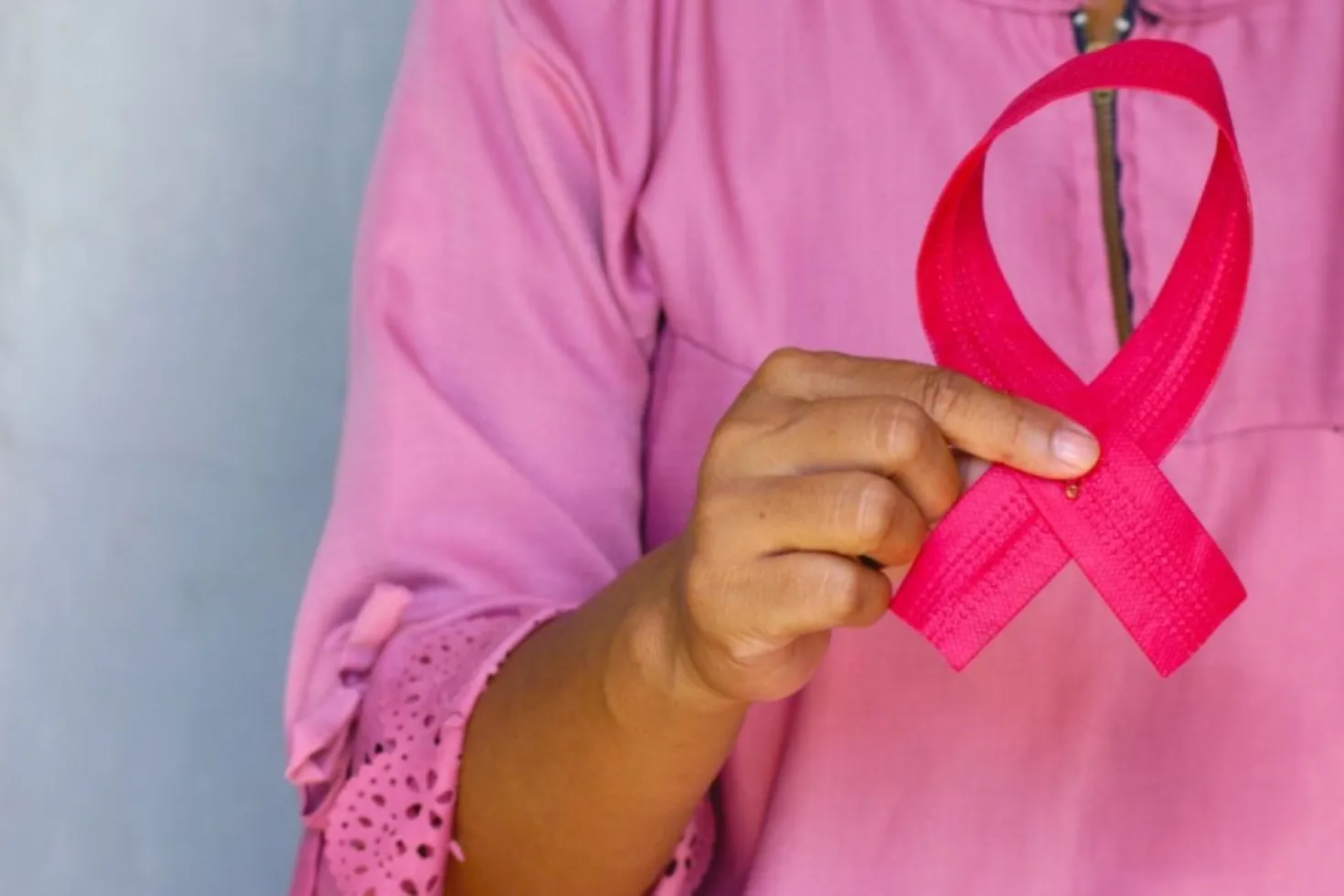 Late diagnosis and low survival rates constitute a common challenge faced by breast cancer organisations in low-income settings around the world. Woman dressed in pink holding a pink ribbon, symbolising breast cancer awareness month