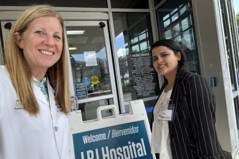 White woman in doctor's overalls with Asian woman with black sweater