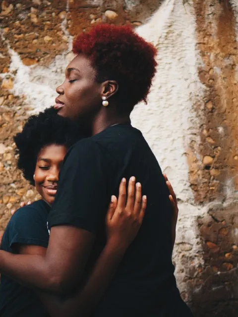 Two black women hugging each other